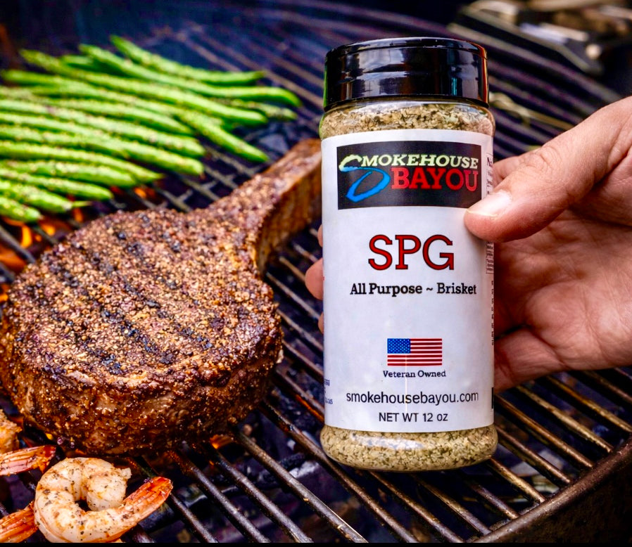 Hand holding a jar of Smokehouse Bayou seasoning over a grill with cooked food.