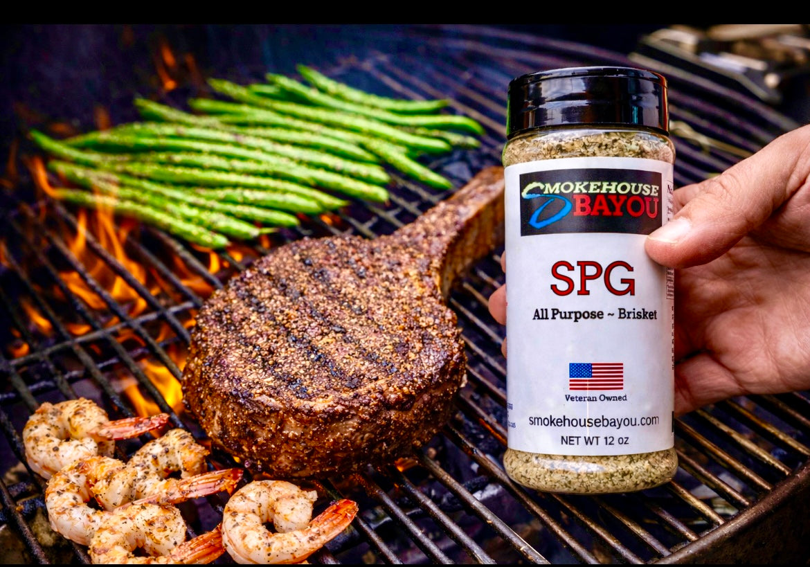 Grilled steak, shrimp, and asparagus on a grill with Smokehouse Bayou seasoning bottle.