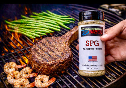 Grilled steak, shrimp, and asparagus on a grill with Smokehouse Bayou seasoning bottle.