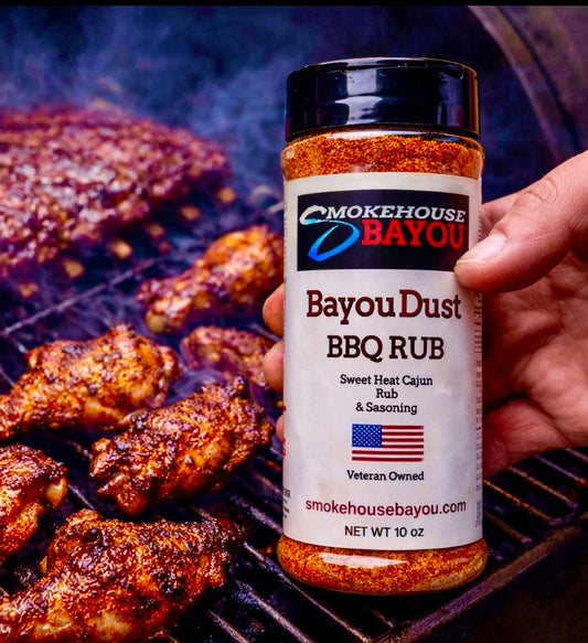 Bayou Dust BBQ Rub container held over grilled chicken on a grill